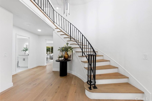 stairs featuring a high ceiling, baseboards, and wood finished floors