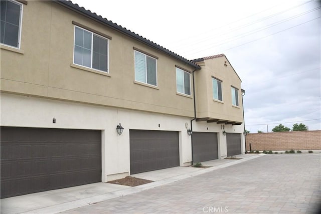 exterior space featuring a tiled roof, an attached garage, and stucco siding