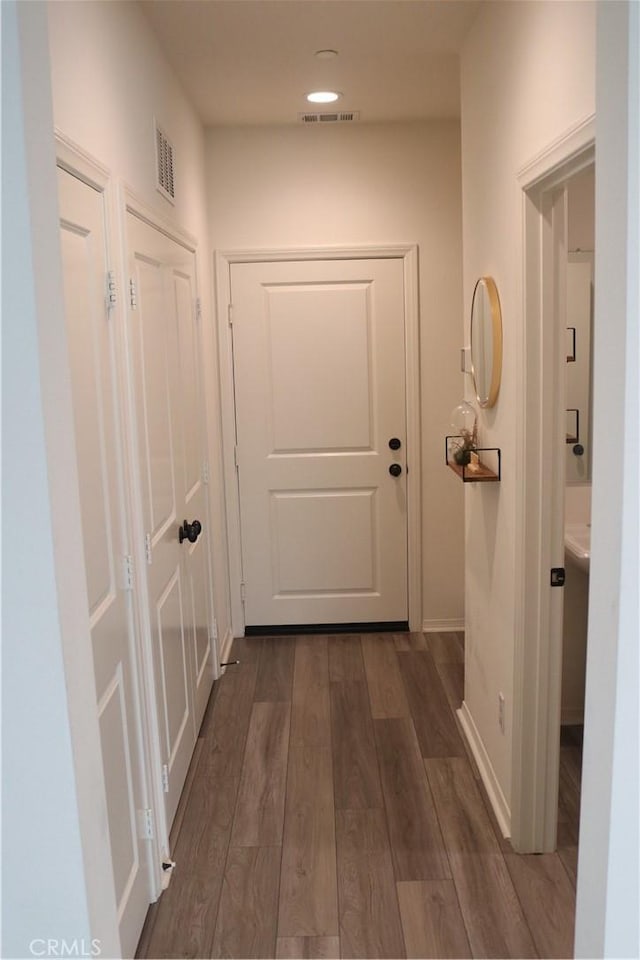 hall with baseboards, visible vents, and dark wood-style flooring