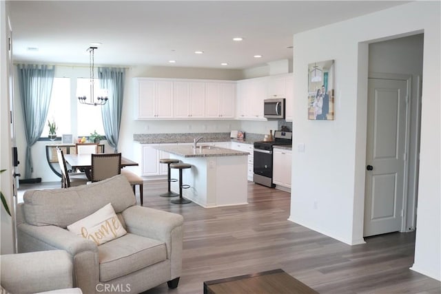 kitchen with a sink, appliances with stainless steel finishes, open floor plan, and white cabinetry