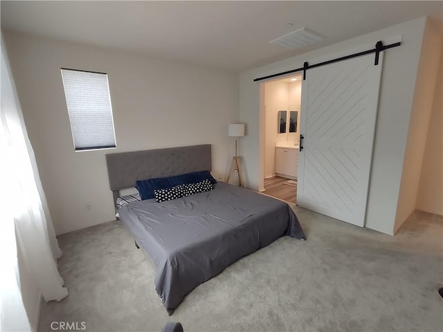 bedroom featuring visible vents, ensuite bath, a barn door, and carpet floors