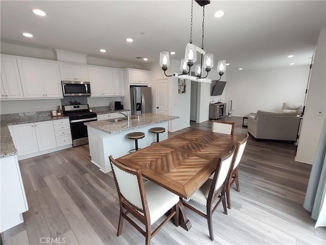 kitchen featuring open floor plan, recessed lighting, appliances with stainless steel finishes, wood finished floors, and white cabinetry