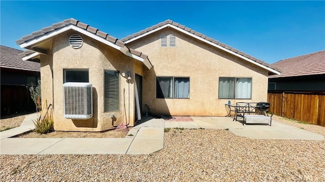 rear view of house featuring a tile roof, a patio area, fence, and stucco siding