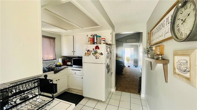 kitchen with plenty of natural light, white cabinets, freestanding refrigerator, and a sink