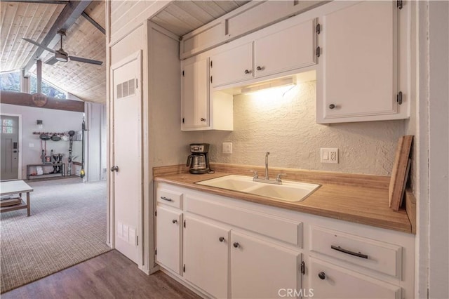 kitchen with visible vents, light countertops, a textured wall, a ceiling fan, and a sink