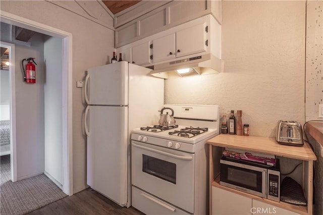 kitchen with under cabinet range hood, light countertops, a textured wall, white cabinets, and white appliances