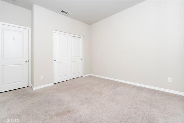 unfurnished bedroom featuring carpet flooring, baseboards, visible vents, and a closet