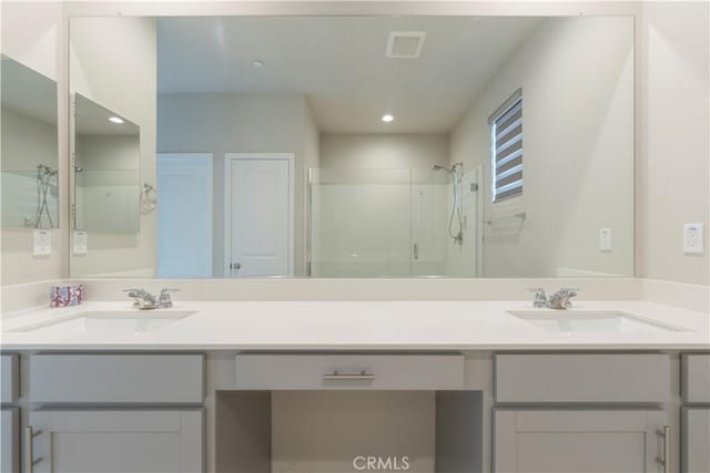 bathroom featuring double vanity, a stall shower, visible vents, and a sink