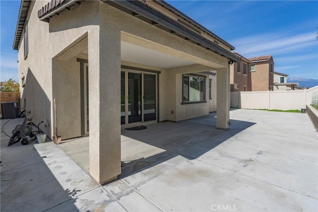 rear view of house featuring cooling unit, a fenced backyard, and stucco siding