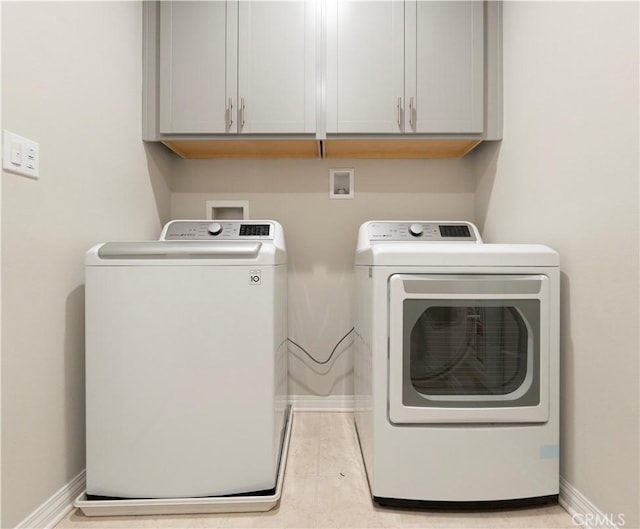 laundry area featuring washer and clothes dryer, cabinet space, and baseboards