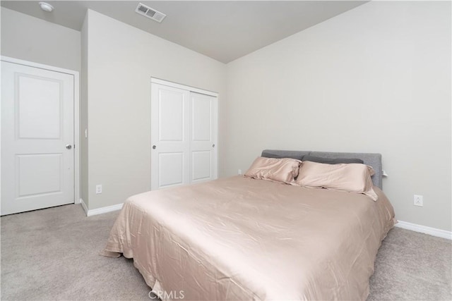 bedroom with baseboards, visible vents, a closet, and light carpet