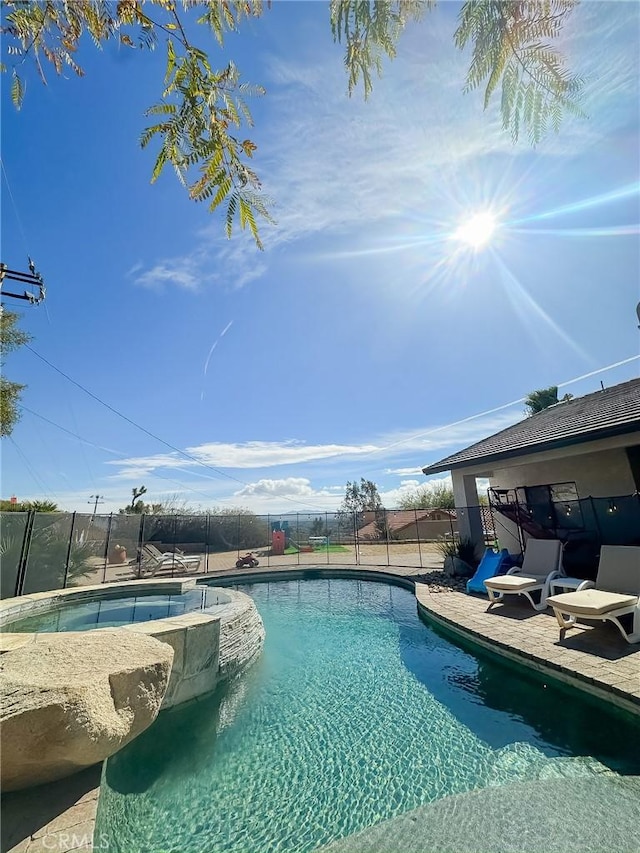 view of pool featuring a patio, a pool with connected hot tub, and fence