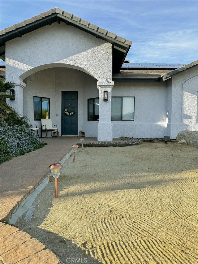 back of house with solar panels and stucco siding