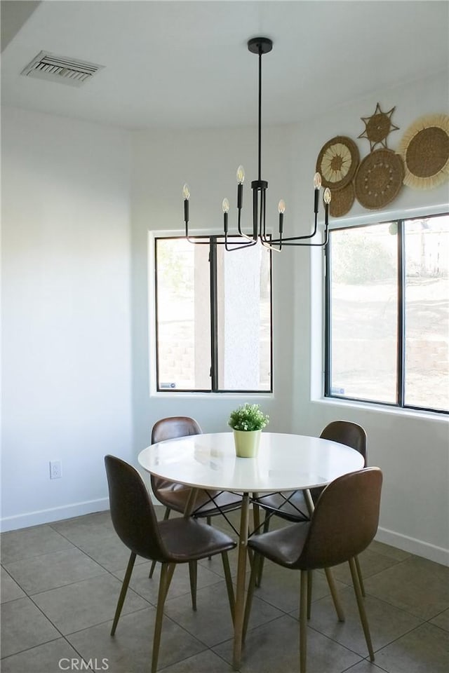 tiled dining space with visible vents, baseboards, and a chandelier