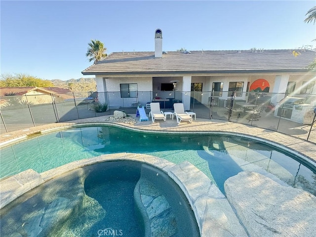 view of swimming pool featuring a patio area, fence, and a pool with connected hot tub