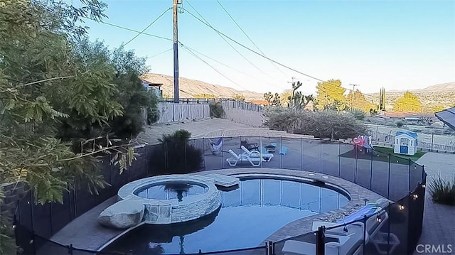 view of pool featuring a fenced in pool, a mountain view, a hot tub, and a fenced backyard