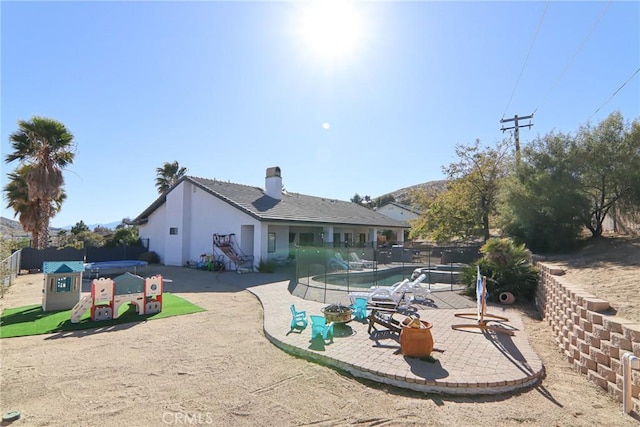 rear view of property featuring a patio, a fenced in pool, a fenced backyard, stucco siding, and a chimney