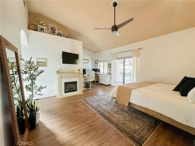 bedroom featuring wood finished floors, high vaulted ceiling, ceiling fan, access to exterior, and a glass covered fireplace