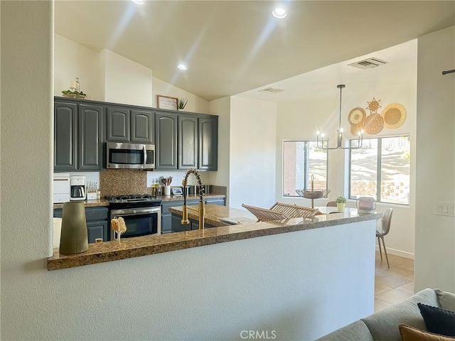 kitchen featuring light tile patterned floors, visible vents, lofted ceiling, a peninsula, and appliances with stainless steel finishes