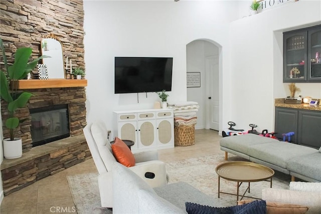 tiled living room with a stone fireplace and arched walkways