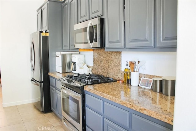 kitchen with stainless steel appliances, backsplash, gray cabinetry, and light tile patterned flooring