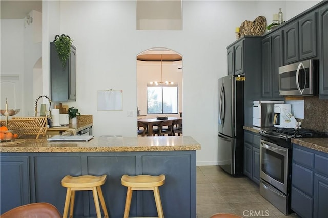 kitchen with a breakfast bar, backsplash, arched walkways, and appliances with stainless steel finishes