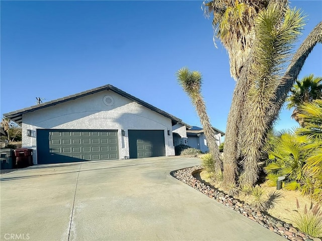 exterior space featuring stucco siding, concrete driveway, and a garage