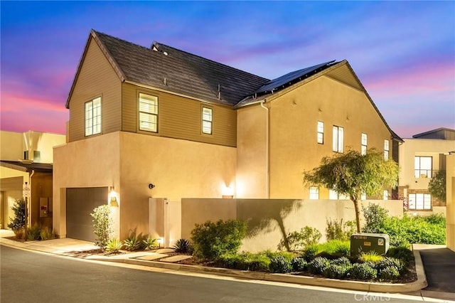 450 Chorus, Irvine, CA 92618 - view of property exterior with a garage, roof mounted solar panels, concrete driveway, and stucco siding