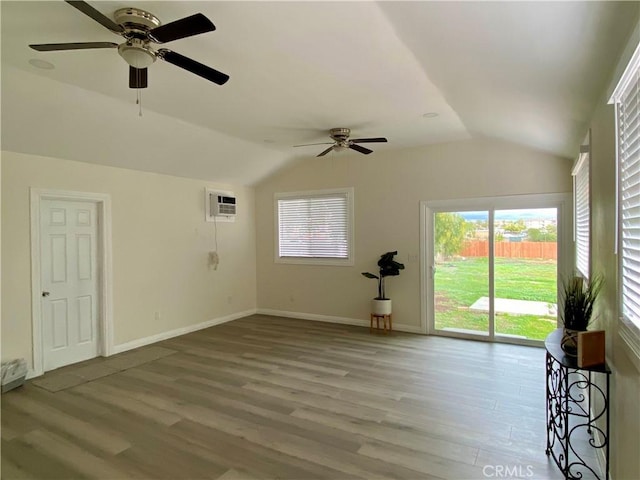 spare room with lofted ceiling, wood finished floors, baseboards, and a wall mounted air conditioner