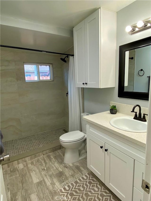 full bath featuring a tile shower, toilet, and vanity