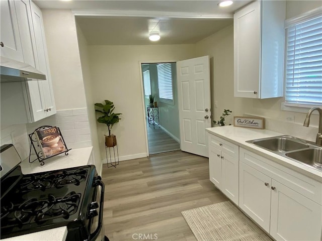 kitchen with gas range, white cabinets, and a sink