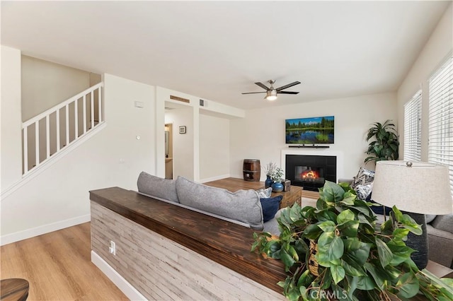 29193 Via Espada, Murrieta, CA 92563 - living area featuring light wood-type flooring, ceiling fan, a fireplace, stairs, and baseboards