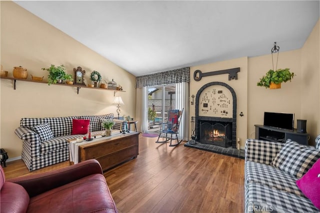 living area with a brick fireplace and wood finished floors