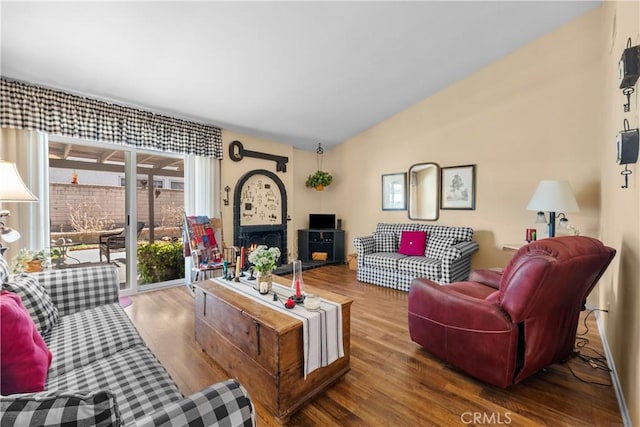 living room featuring lofted ceiling, wood finished floors, and a fireplace