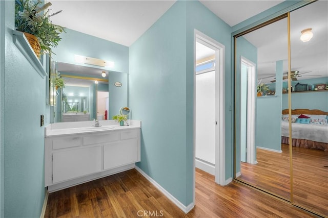 ensuite bathroom with connected bathroom, baseboards, wood finished floors, vanity, and a ceiling fan