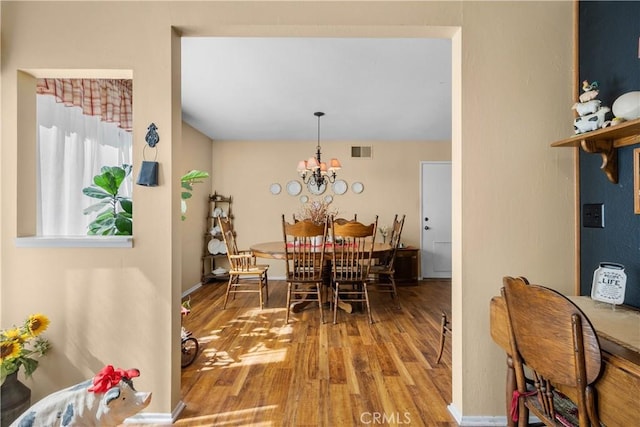 dining area with visible vents, baseboards, a notable chandelier, and wood finished floors