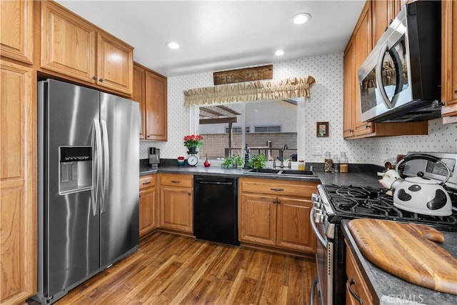 kitchen with dark countertops, appliances with stainless steel finishes, wallpapered walls, and wood finished floors