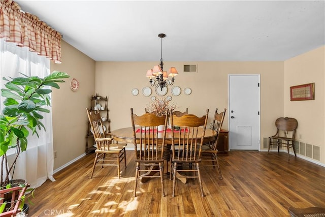 dining space featuring visible vents, baseboards, wood finished floors, and a chandelier