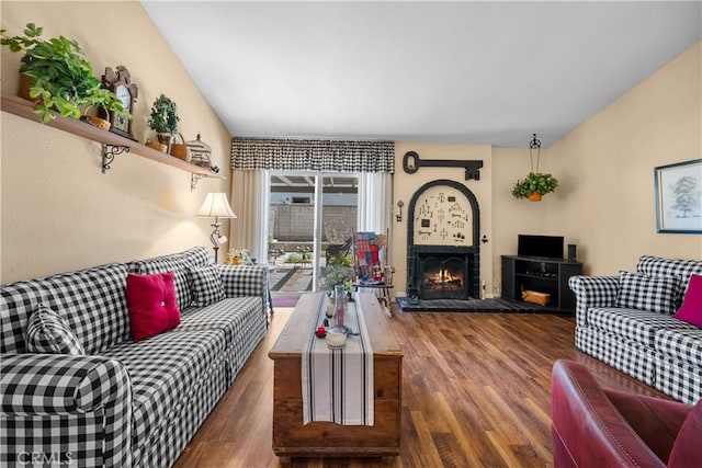 living room with a warm lit fireplace and wood finished floors