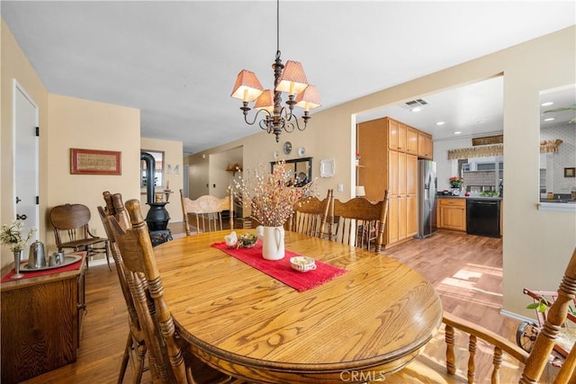 dining area featuring a notable chandelier, visible vents, and light wood-style floors