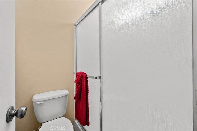 bathroom featuring toilet and a shower stall