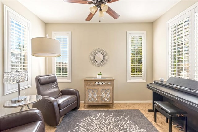 living area featuring a wealth of natural light, ceiling fan, tile patterned floors, and baseboards