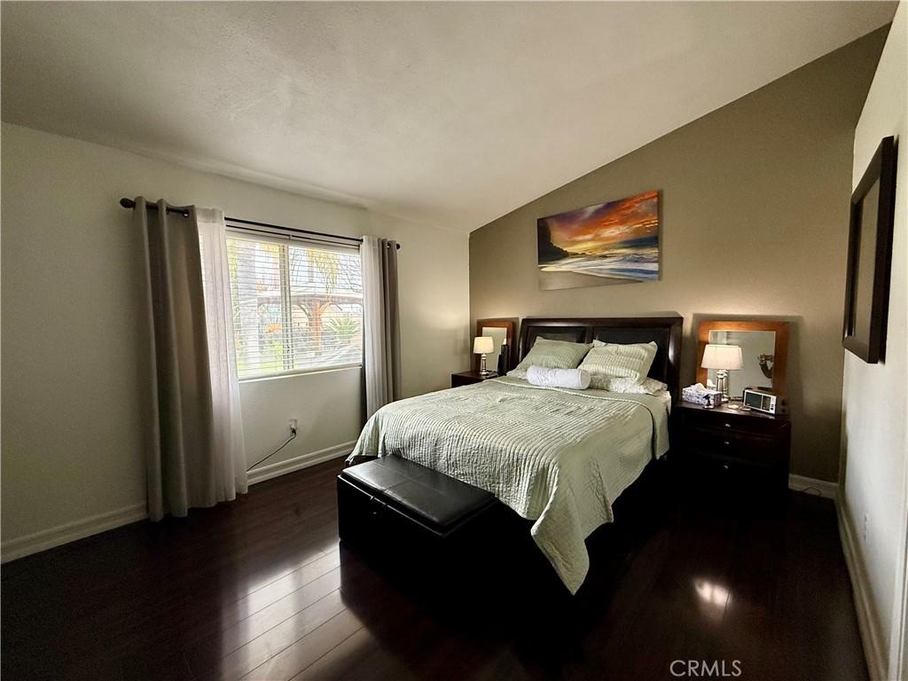 bedroom featuring vaulted ceiling, baseboards, and dark wood-style flooring