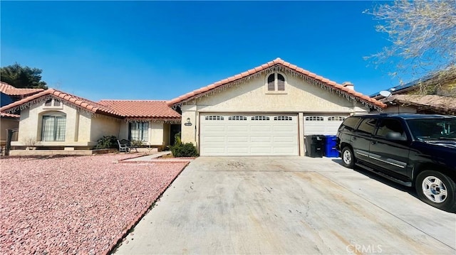 view of front of house with stucco siding, driveway, a tile roof, and an attached garage