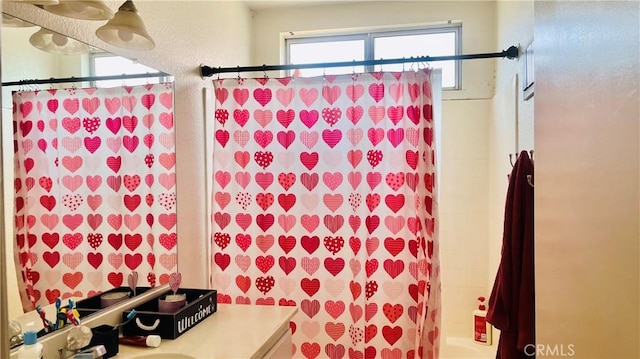 bathroom with vanity, a textured wall, and shower / tub combo with curtain