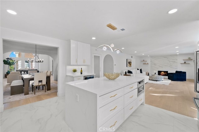 kitchen with marble finish floor, open floor plan, recessed lighting, arched walkways, and a fireplace