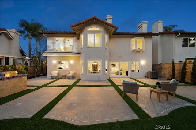 rear view of house with stucco siding, a patio, and fence