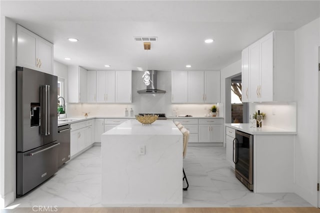 kitchen with wall chimney range hood, marble finish floor, wine cooler, and stainless steel appliances