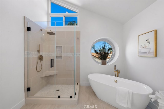 bathroom with a shower stall, baseboards, and a freestanding bath