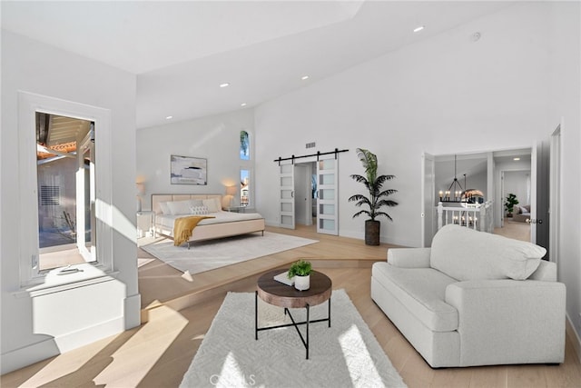 bedroom featuring a barn door, recessed lighting, an inviting chandelier, wood finished floors, and high vaulted ceiling